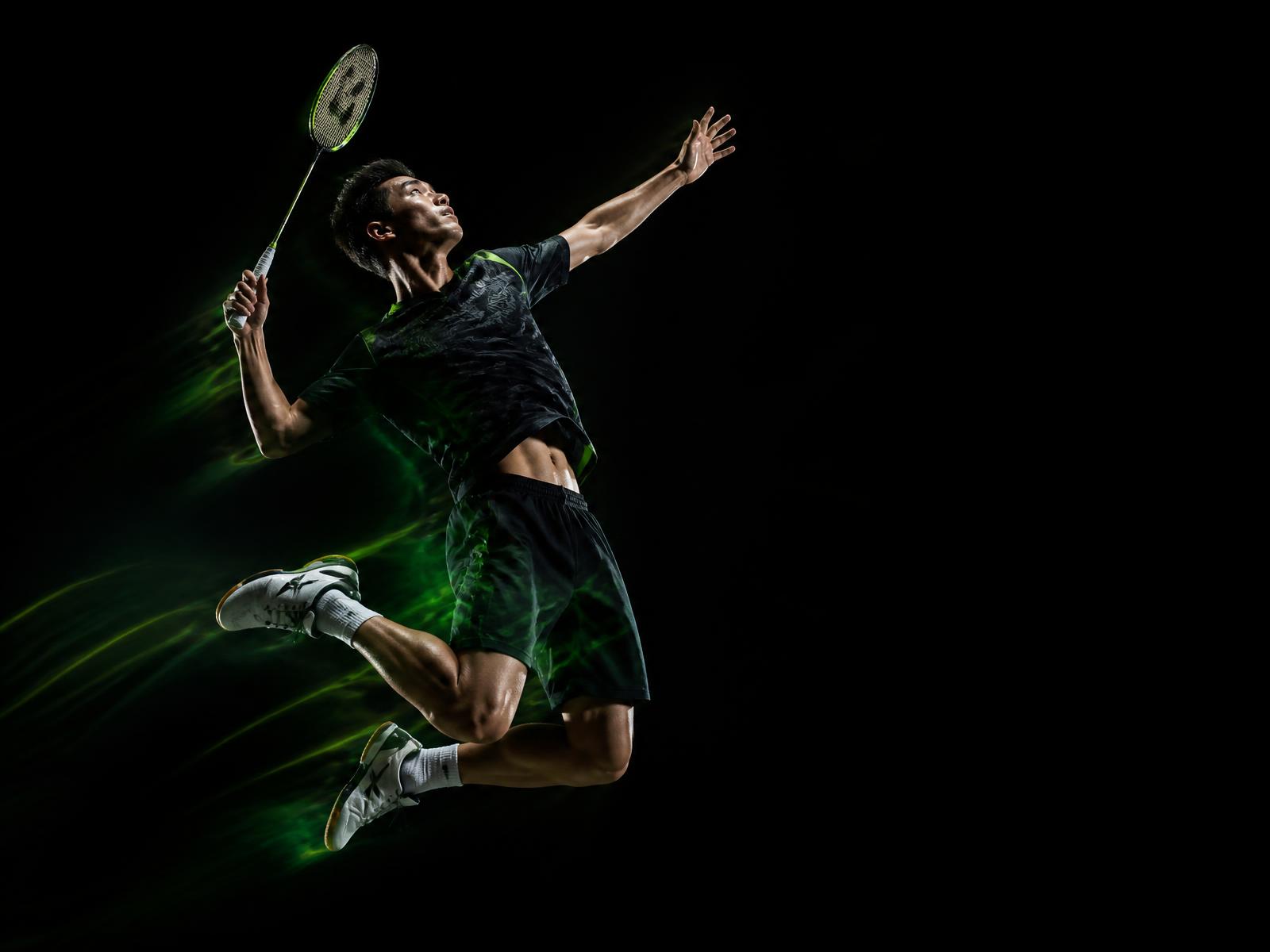Badminton player leaping for a smash under dramatic arena lighting